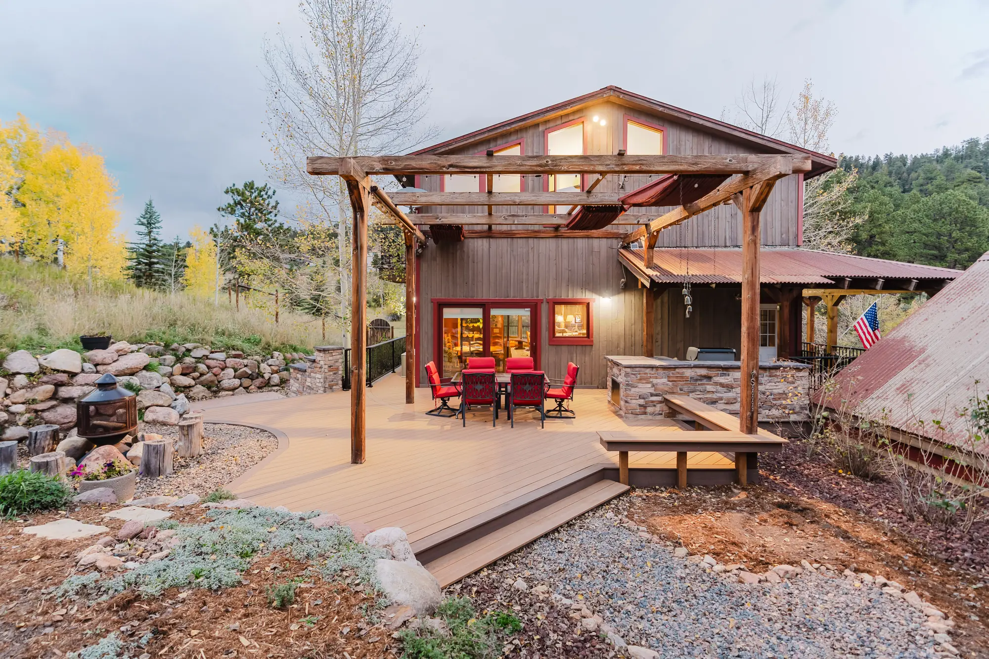 Custom deck with wide steps, a timber pergola and a dining set beside a rustic home